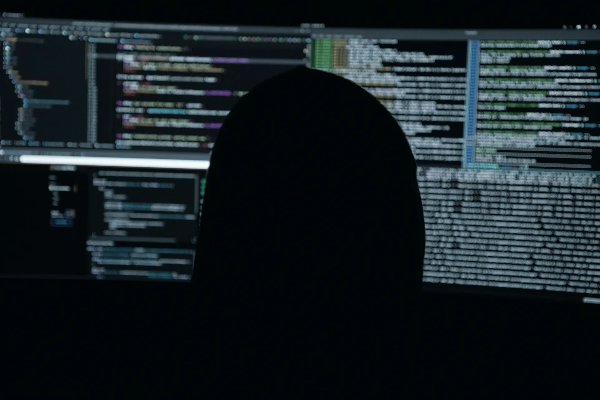 Pessoa diante de monitores com código e dados